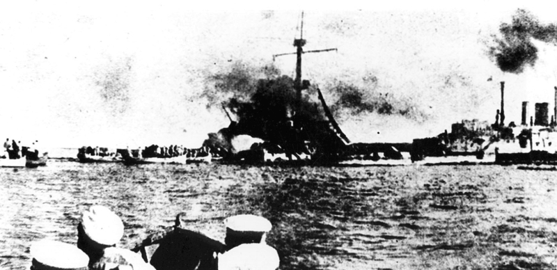 La nave si incendia e si adagia sul fondale del porto. In secondo piano la corazzata gemella Regina Margherita