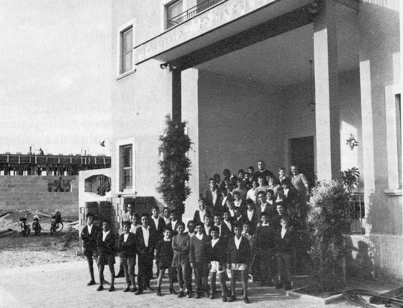 Un gruppo di ragazzi con don Giuseppe Cavaliere davanti all'ingresso dell'istituto